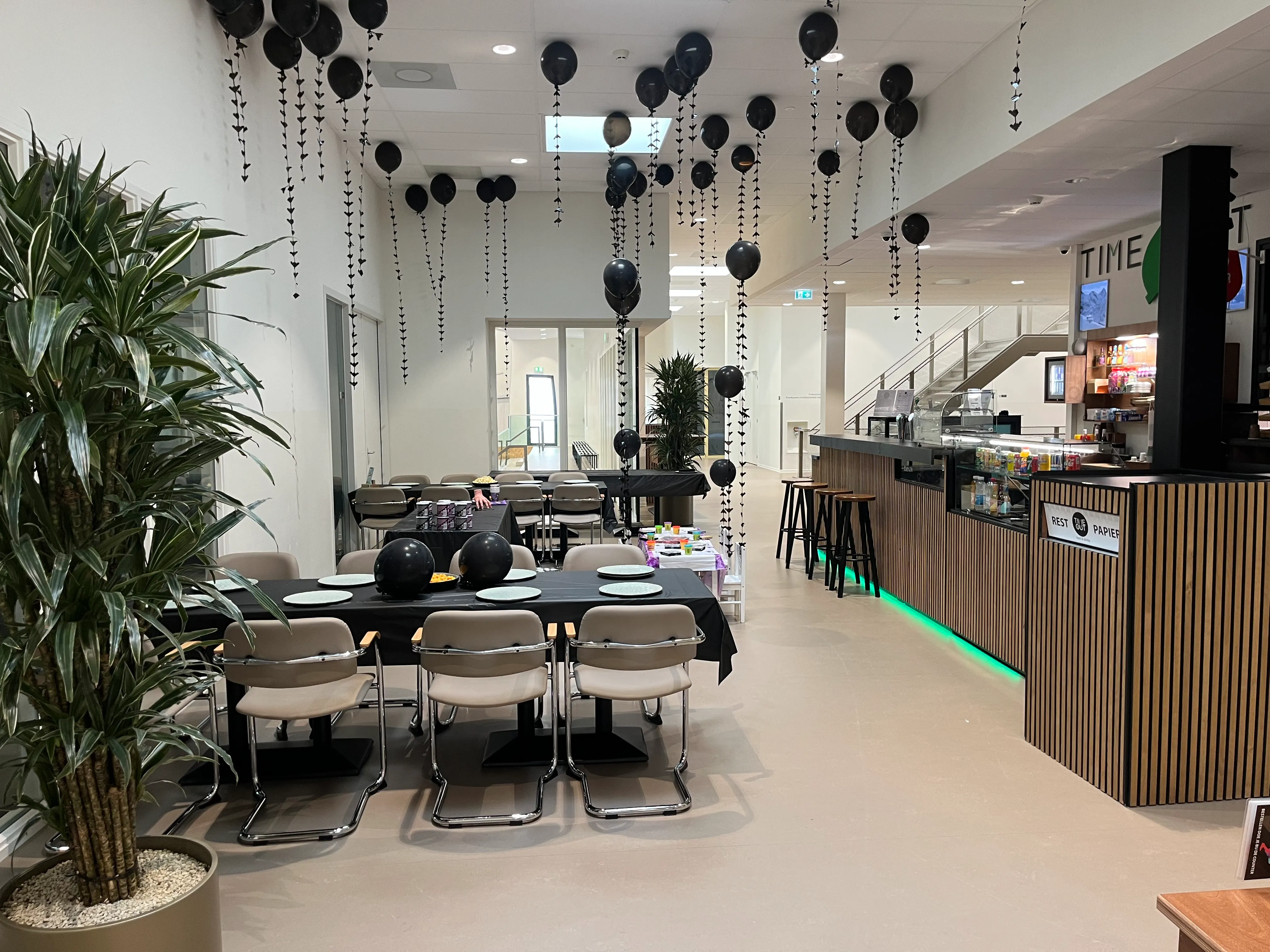 Feestzaal met zwarte ballonnen en gedekte tafels